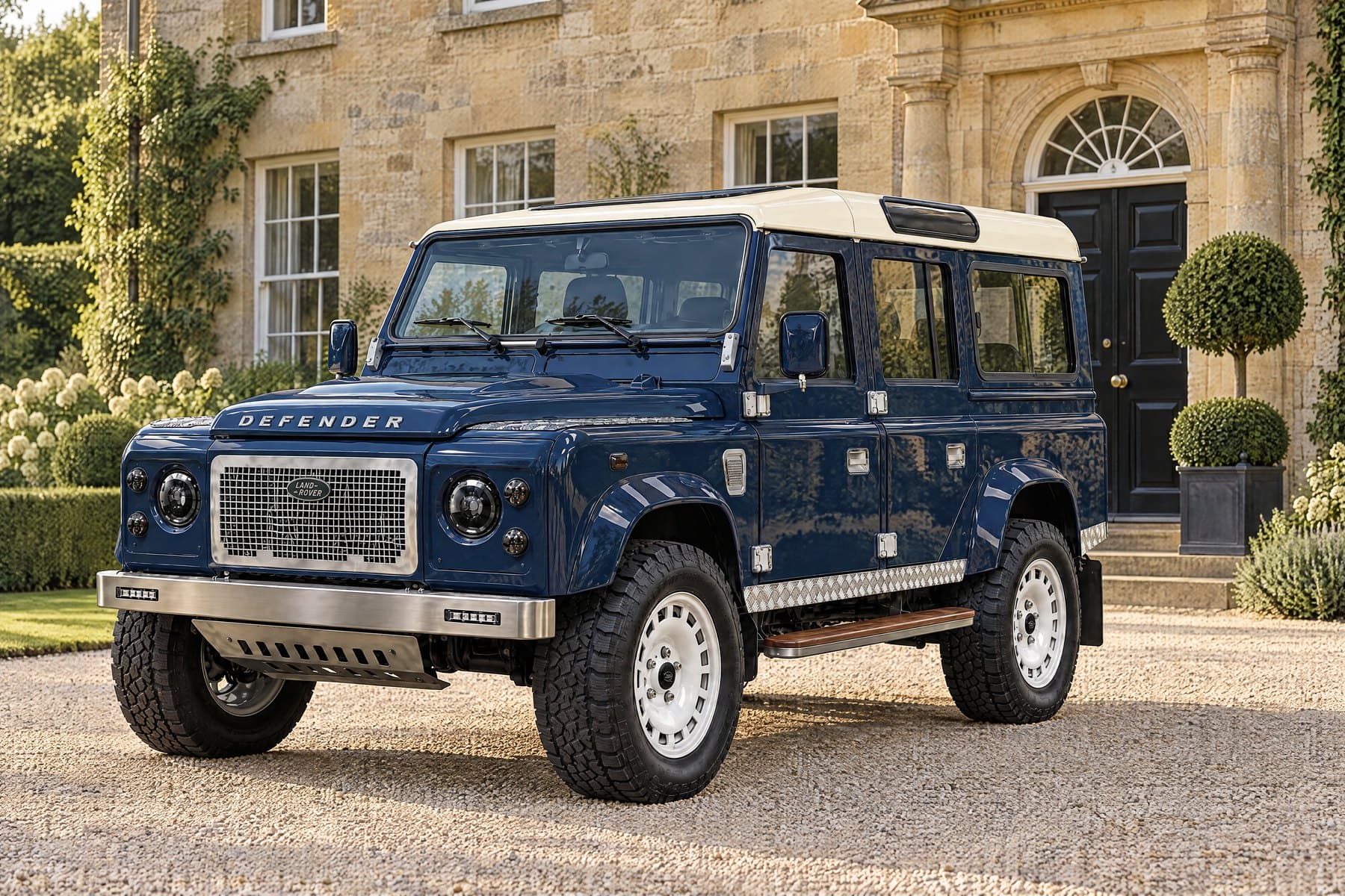 Oxford Blue Defender 110 with an ivory roof on a gravel forecourt in front of a stone house